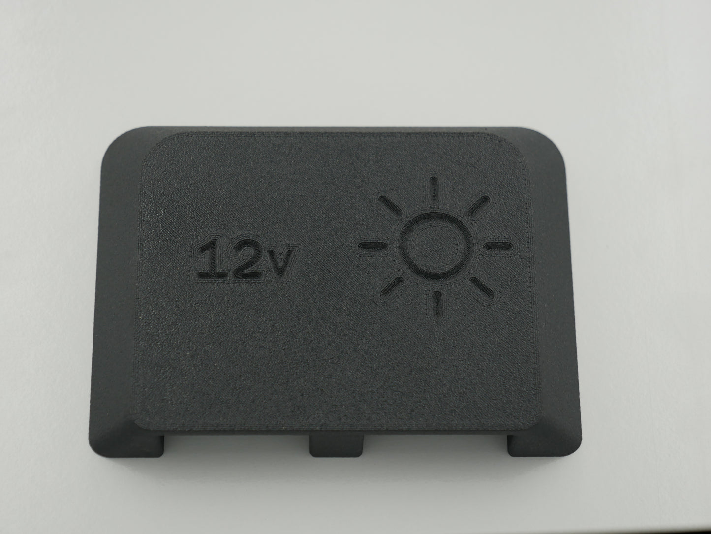 Black rectangular component with '12v' and sun symbol on a white background