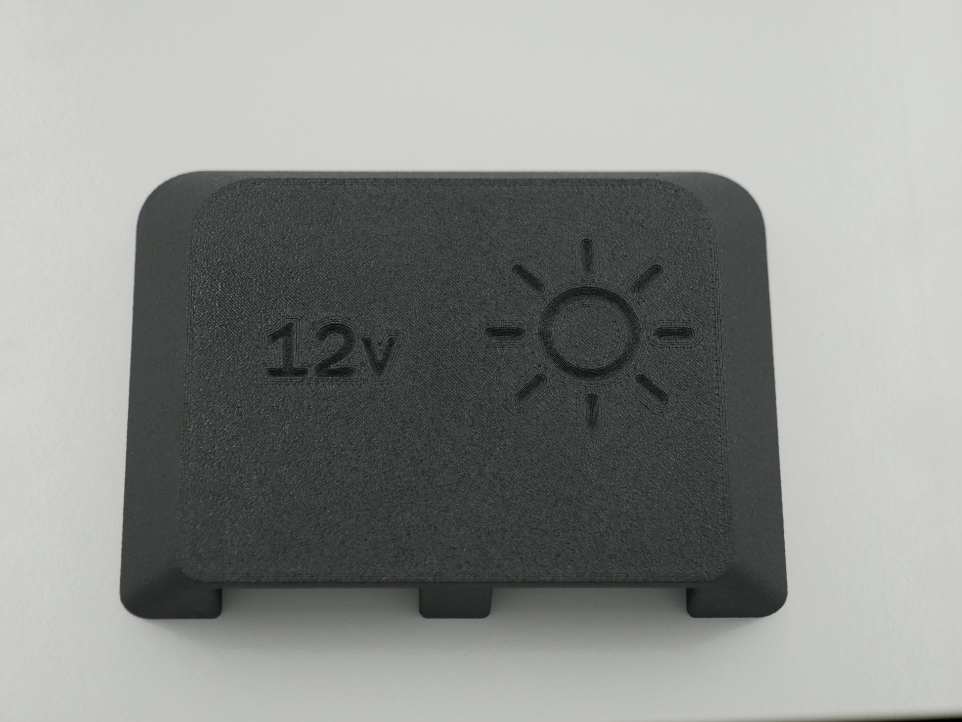 Black rectangular component with '12v' and sun symbol on a white background